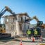 Residential demolition site with machinery and workers, highlighting safe demolition practices